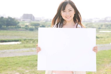 Gülümseyen Japon kadın elinde boş kağıt tutuyor.