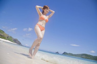 Genç Japon kadın sahilde bikinili poz veriyor.