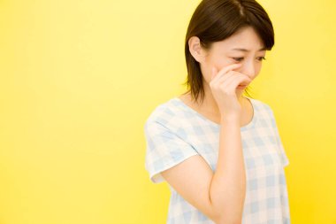 Sarı arka planda ağlayan Asyalı genç kadın