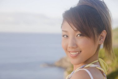 Arka planda deniz manzaralı gülümseyen Asyalı kadın portresi