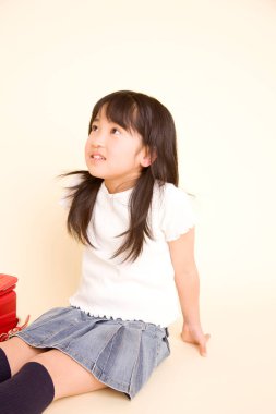 Yerde oturan sevimli Asyalı küçük kız 