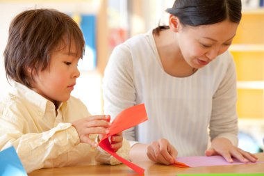 Küçük tatlı çocuk Japon anaokulunda öğretmenle oynuyor.