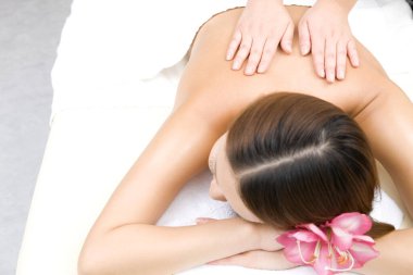 Güzel genç bir kadın güzellik merkezinde sırt masajı yaptırıyor.