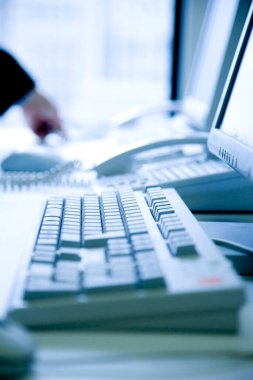 Bilgisayar klavyesi ve telefon ofis masasında.