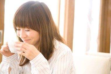 Kafede bir fincan kahve içen genç Asyalı kadın.