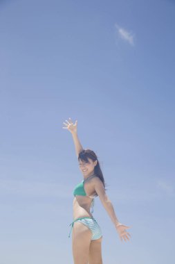 Genç Japon kadın sahilde bikinili poz veriyor.