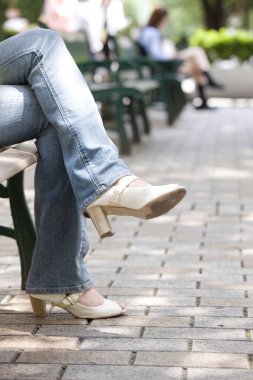 Kadın bankta oturuyor, ekin manzaralı.