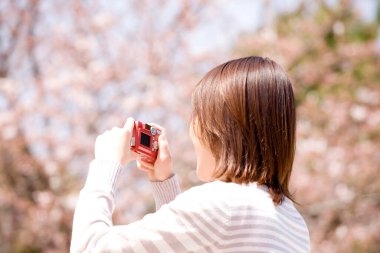 Kırmızı kamerayla fotoğraf çeken bir kadın.