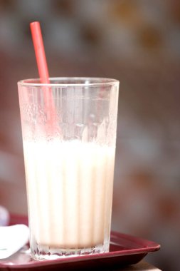 Masanın üzerinde bir bardak süt ve buz.