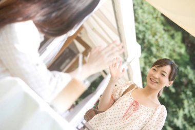 Genç kadınlar açık kafede birbirlerine el sallıyorlar. 