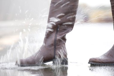 Botlu bir kadın, sonbahar mevsiminde yağmurda yürür.