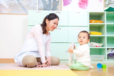 Küçük tatlı çocuk Japon anaokulunda öğretmenle oynuyor.