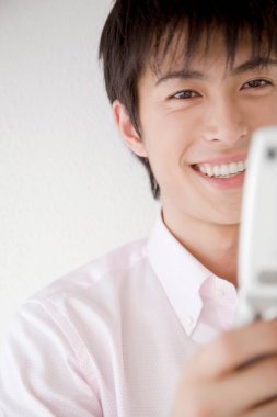 Asyalı genç bir adamın telefonlu portresini kapat. 