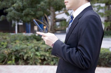 Takım elbiseli yakışıklı bir Japon iş adamının dışarıda poz verirken portresi.