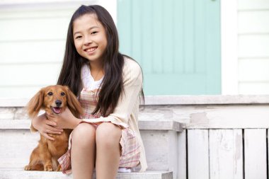 Şirin, mutlu Japon kızın yavru köpeğiyle portresi.