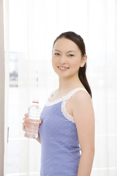 Mooie Jonge Aziatische Vrouw Houden Fles Water Glimlachen Thuis — Stockfoto