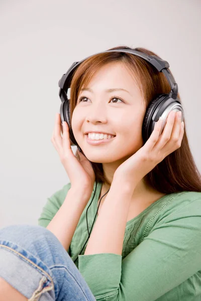 Japanese woman listening music. Beauty lady sitting in headphones