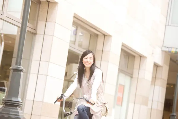 美丽而快乐的年轻亚洲女人在城市骑自行车 — 图库照片