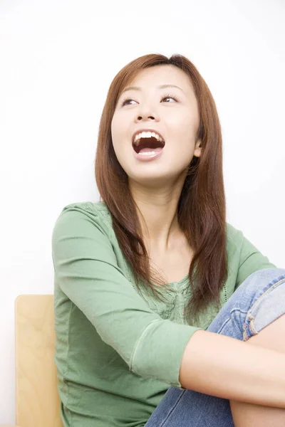 一个快乐的日本女人坐在家中沙发上的画像 — 图库照片
