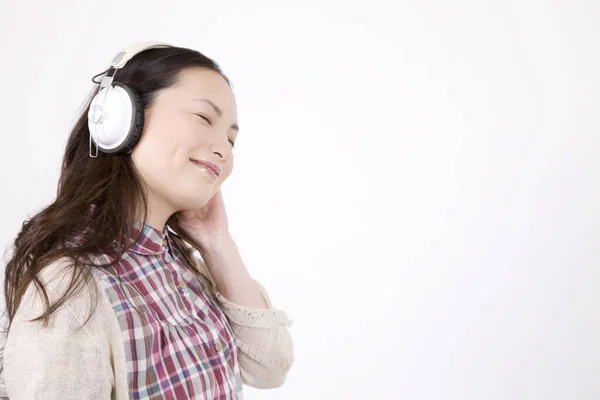 白い背景に隔離されたヘッドホンで音楽を聞く美しい若い女性の肖像画 — ストック写真