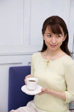 Elinde kahve tutan Asyalı genç bir kadın.