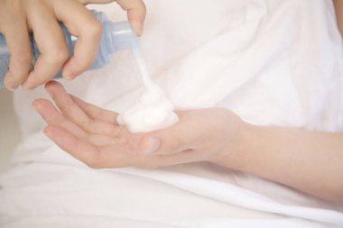 Kadın eline nemlendirici krem sürüyor.  