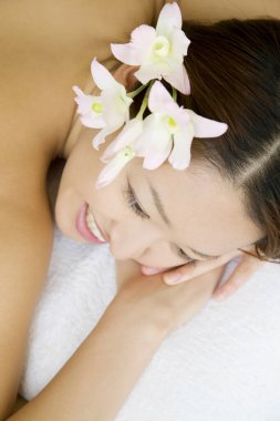 Güzel Asyalı kadın portresi. Saçında çiçekler, kaplıcada yatıyor.