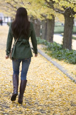 Sarı sonbahar parkında genç bir kadın.