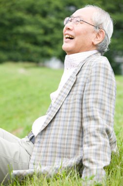 Asyalı kıdemli adam parkta dinleniyor.