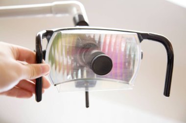 Bir dişçi lambasıyla elini kapat.