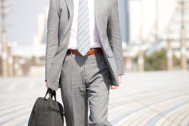 Elinde bavuluyla şehirde yürüyen bir iş adamı.