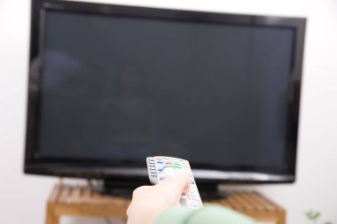 Uzaktan kumandayı televizyonun önünde tutan kişi.