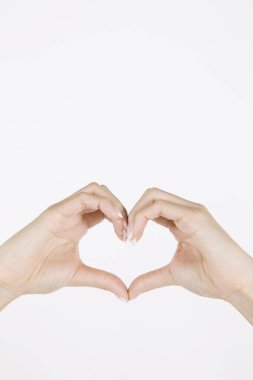 Beyaz arka planda kalp şekillendiren kadın elleri