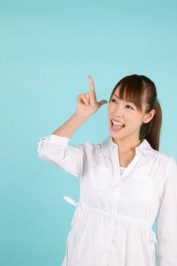 Güzel, genç Asyalı bir kadın mavi arka planda izole edilmiş.