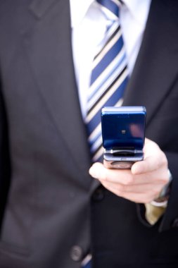 Elinde cep telefonu olan takım elbiseli bir adam.