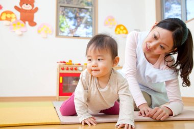 Küçük tatlı çocuk Japon anaokulunda öğretmenle oynuyor.