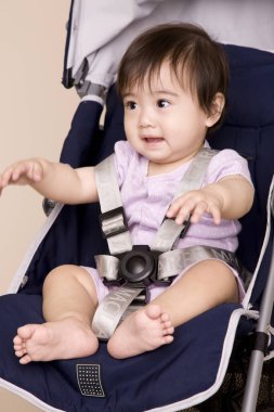 Bebek arabasında oturan sevimli Asyalı bebek.