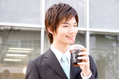 Ofisinin yanında kahve fincanı olan genç Asyalı iş adamı. 