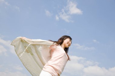 Mavi gökyüzüne gülümseyen genç Asyalı kadın