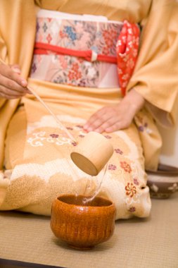 Geleneksel Japon çay töreninde kimono giyen ve matcha çayı hazırlayan bir kadın.   