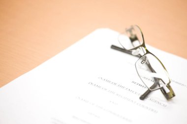 Ofis masasındaki belgede bir çift gözlük.