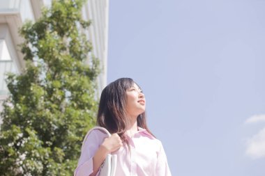 Güzel, mutlu Asyalı bir kadın şehirde yürüyor.