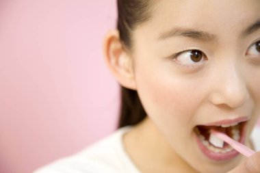 Genç Asyalı kız dişlerini fırçalıyor.