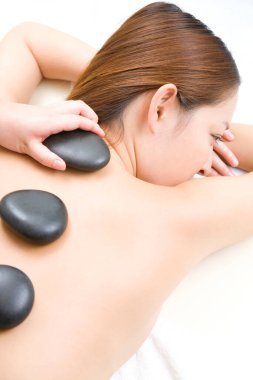 Asyalı kadın güzellik salonunda spa taşı terapisi görüyor.