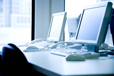 İki masaüstü bilgisayarı ve telefonu olan ofis masası.