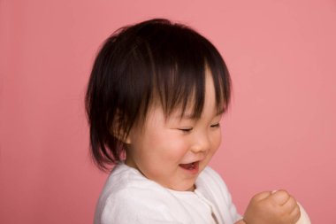 Pembe arka planda oynayan Asyalı çocuk