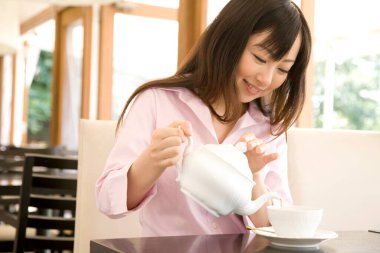 Kafeye çay döken güzel Japon kadının yakın görüntüsü.