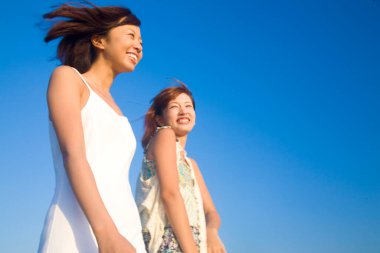 Mavi gökyüzünde mutlu Asyalı kadınlar