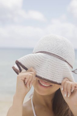 Sahilde poz veren beyaz şapkalı güzel bir kadın.