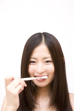 Asyalı kadın diş fırçasıyla dişlerini fırçalıyor